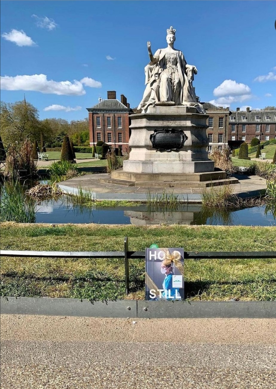 نسخة الكتاب في مواجهة السور المنخفض حول البركة حيث يلوح تمثال الملكة فيكتوريا التذكاري- الصورة من حساب دوق ودوقة كامبريدج على إنستغرام.jpg
